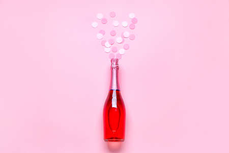 Bottle of champagne and confetti on color background. New Year celebrationの写真素材