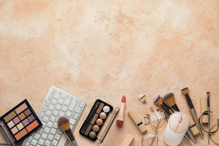 Computer keyboard and decorative cosmetics on color background