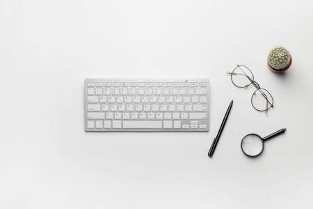 Composition with computer keyboard, eyeglasses and magnifying glass on white backgroundの写真素材