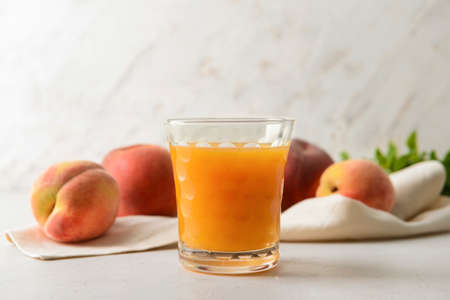 Glass of fresh peach juice on table