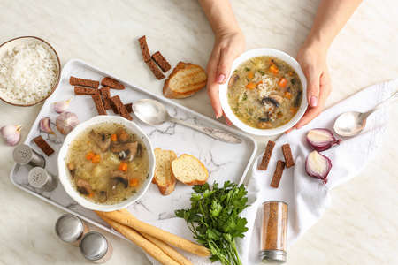 Woman with tasty rice soup at table