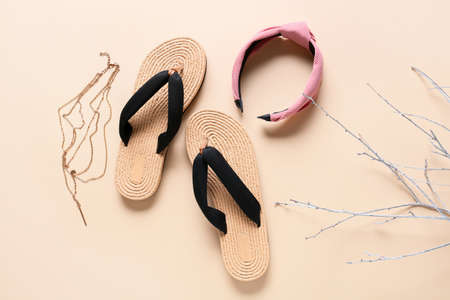 Stylish female flip-flops and accessories on light background