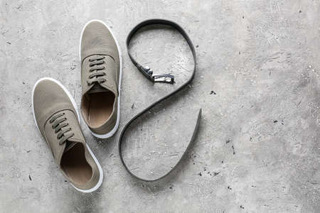 Stylish shoes and leather belt on light background