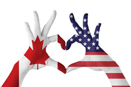 Hands painted in colors of Canadian and USA flags making heart on white backgroundの写真素材
