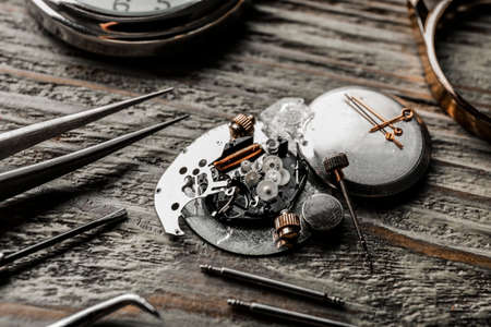 Watch and tools for repair on wooden background