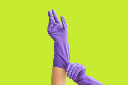 Woman putting on rubber gloves against color backgroundの写真素材