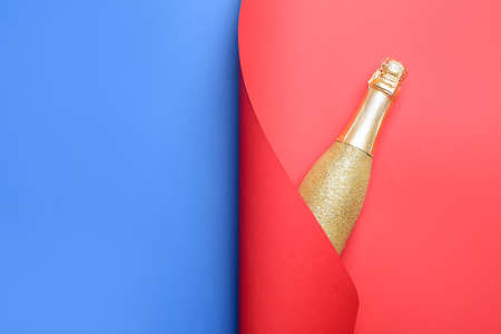 Bottle of champagne wrapped in paper on color backgroundの写真素材
