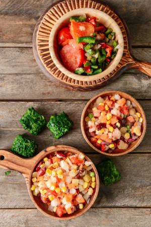 Frozen vegetables in bowls on wooden background