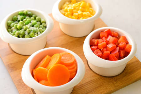 Frozen vegetables in bowls on light backgroundの写真素材