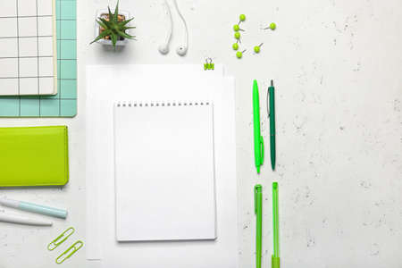 Composition with blank paper sheet and stationary on light background