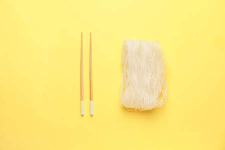Raw rice noodles with chopsticks on color backgroundの写真素材