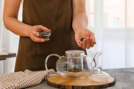 Woman brewing green tea in pot at homeの写真素材