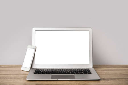 Modern laptop and mobile phone on table in office