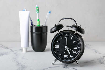 Alarm clock, paste and toothbrushes on table