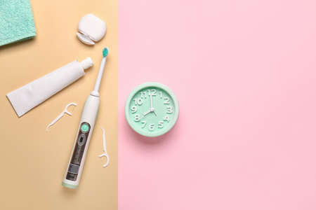 Set of oral care products and alarm clock on color backgroundの写真素材