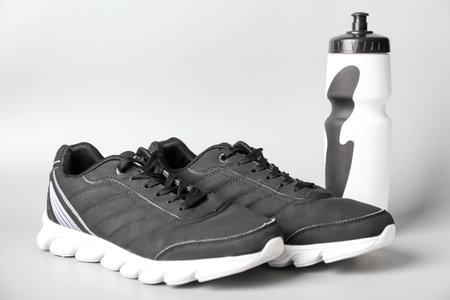 Sportive shoes and bottle of water on white backgroundの写真素材