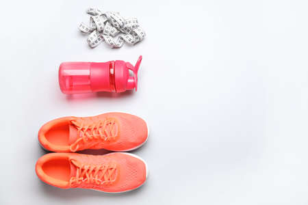 Sportive shoes, bottle of water and measuring tape on white backgroundの写真素材