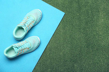 Sportive shoes and yoga mat on color backgroundの写真素材