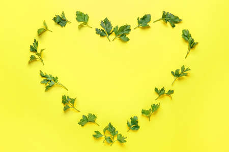 Heart made of fresh parsley on color background