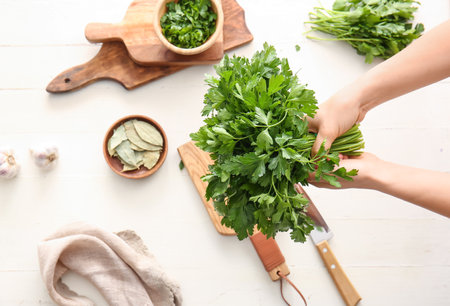Woman with fresh parsley at tableの写真素材
