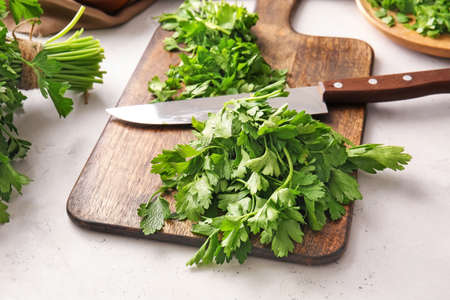 Cutting board with fresh parsley and knife on tableの写真素材