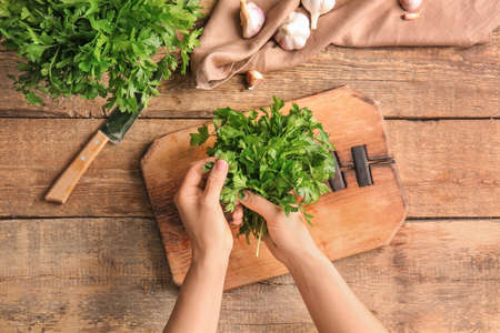 Woman with fresh parsley at tableの写真素材