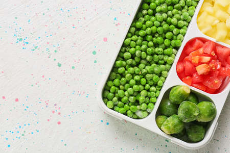 Divided box with different frozen vegetables on white backgroundの写真素材