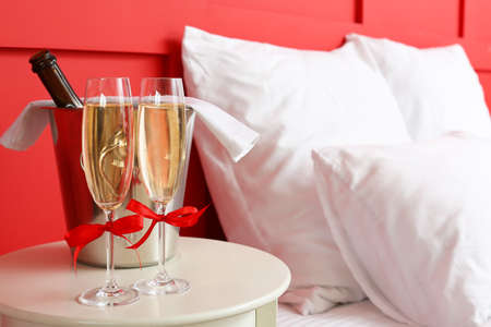 Glasses of champagne and ice bucket on table in hotel roomの写真素材