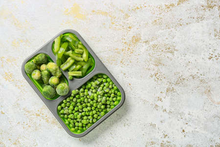 Divided box with different frozen vegetables on white backgroundの写真素材