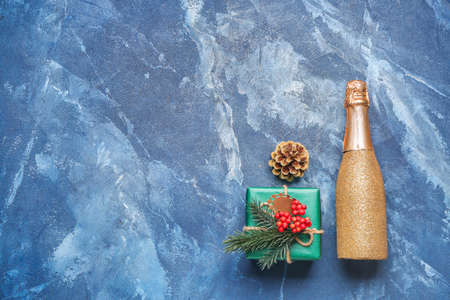Christmas gift with bottle of champagne on color backgroundの写真素材