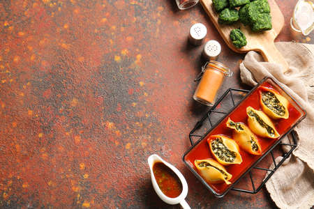 Baking dish with tasty conchiglioni pasta on color backgroundの写真素材