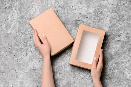 Hands with cardboard box on dark background