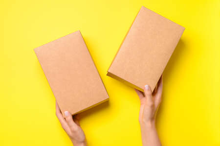 Hands with cardboard boxes on color background