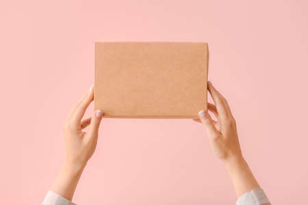 Hands with cardboard box on color backgroundの写真素材