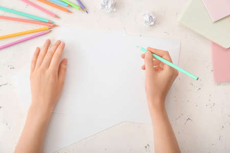 Female hands with blank paper on light backgroundの写真素材