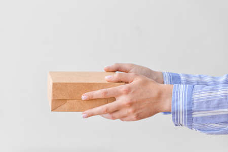 Hands with cardboard box on light backgroundの写真素材