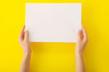 Female hands with blank paper on color backgroundの写真素材