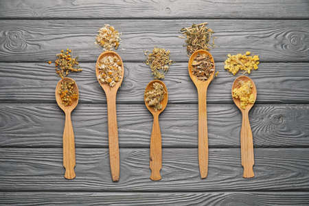 Spoons with different herbs on dark wooden backgroundの写真素材