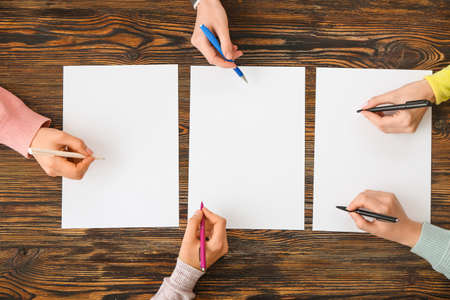 People hands with blank papers on wooden background