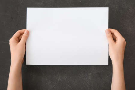 Female hands with blank paper on dark background