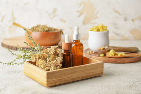 Wooden box with different herbs and bottles of essential oil on tableの写真素材