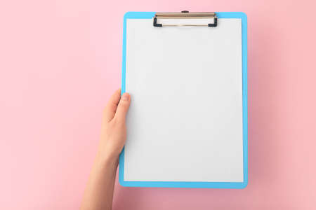 Female hands with blank clipboard on color backgroundの写真素材