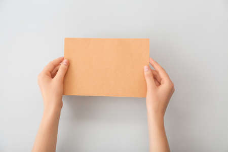 Female hands with blank paper on light background