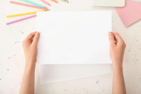 Female hands with blank paper on light backgroundの写真素材