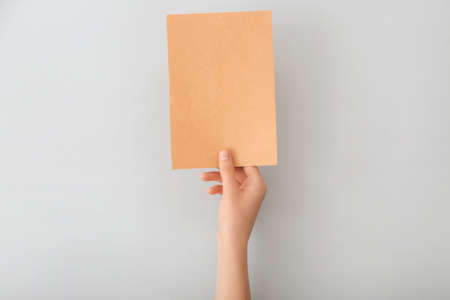 Female hand with blank paper on light background