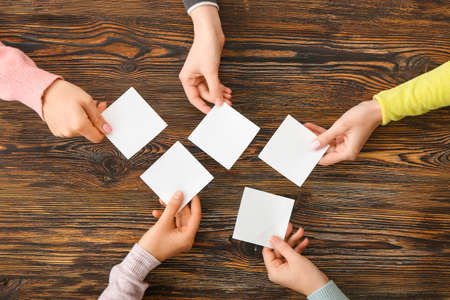 People hands with blank papers on wooden backgroundの写真素材