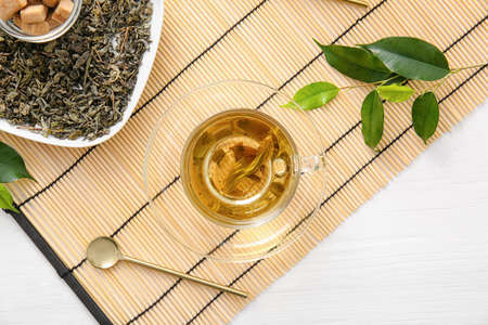 Cup of green tea and dry leaves on bamboo matの写真素材