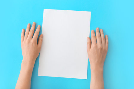 Female hands with blank paper on color backgroundの写真素材