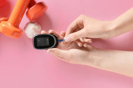 Female hands with glucometer on color background. Diabetes conceptの写真素材