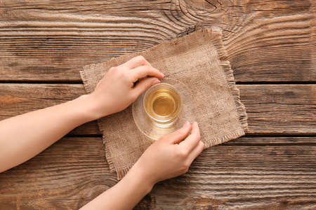 Female hands with cup of green tea on wooden tableの写真素材